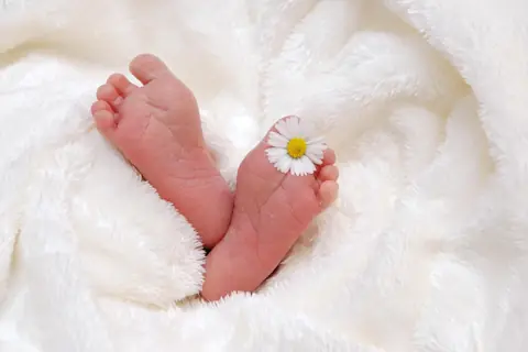 꽃 한 송이를 둔 아기 발